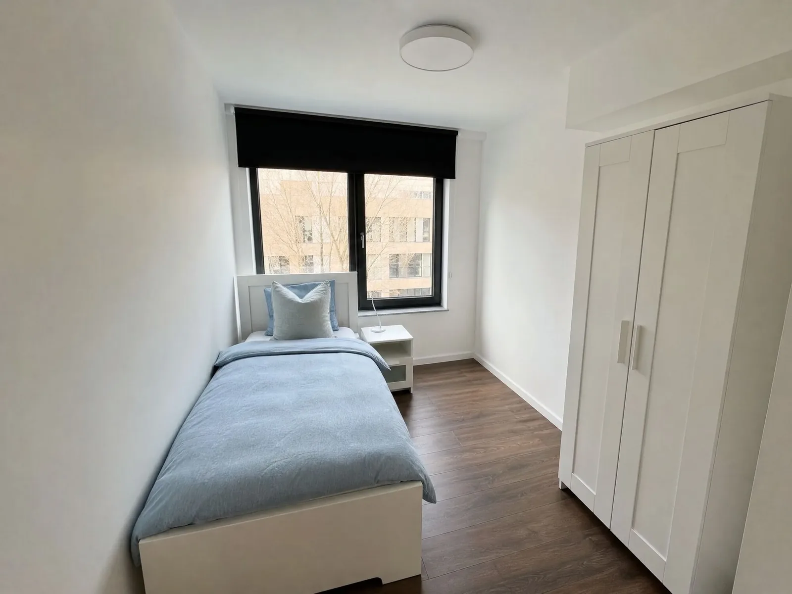 Einzelzimmer mit Bett und großem Fenster